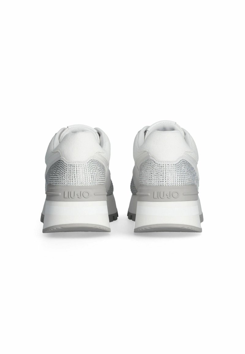 Witte sportieve schoenen met grijze accenten, met een gebreide bovenkant, een getextureerde hak en een dikke witte zool. Logo weergegeven op de hak.