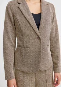 Blazer marrone con motivo a spina di pesce, chiusura a un bottone, rever a risvolto e tasche laterali, realizzato in tessuto testurizzato.