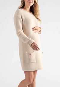Beiges Strickkleid mit lockerer Passform, strukturiertem Stoff, langen Ärmeln und zwei vorderen Taschen mit Holzknopfverschluss.