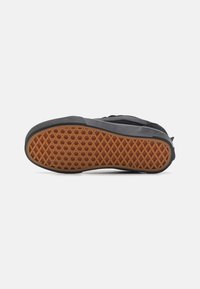 Baskets noires avec une semelle en caoutchouc texturée présentant un motif hexagonal brun. Renfort au niveau de la pointe et des panneaux latéraux pour plus de durabilité.