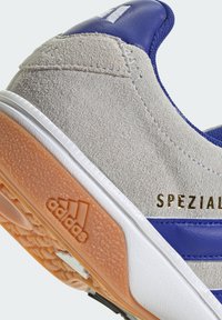 Gray suede upper with blue accents, white sole, and orange textured outsole; features gold "SPEZIAL" branding and three white stripes.