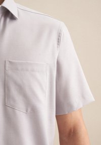 Camicia grigia chiara a maniche corte realizzata in tessuto morbido, dotata di taschino sul lato sinistro del petto e di un colletto tradizionale con cuciture ordinate.