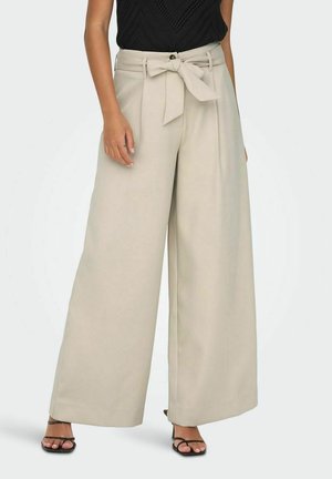 Pantalons beige à jambes larges avec une ceinture à nouer à la taille, fabriqués en tissu léger ; présentent une texture lisse et une coupe ample.