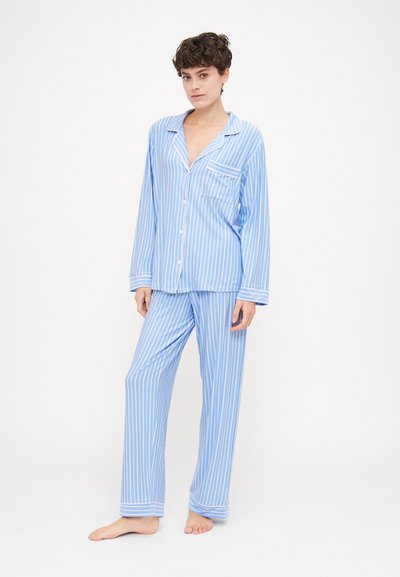 Conjunto de pijama azul e branco com riscas, feito de tecido leve; inclui uma camisa de mangas compridas com um bolso e calças combinando com punhos.