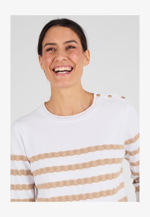 Witte trui met beige afwisselende horizontale strepen en een textuur van golfmotieven. Decoratieve knopen op de schouder voegen detail toe.
