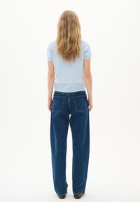 Top azzurro chiaro a maniche corte con orlo a costine abbinato a jeans scuri a vita alta e gamba dritta, caratterizzati da due tasche posteriori e una leggera usura.