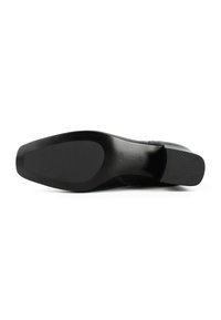 Sole di scarpa nera con una superficie liscia, forma sagomata e tacco in gomma testurizzata. Presenta segni di misura visibili sulla parte inferiore.