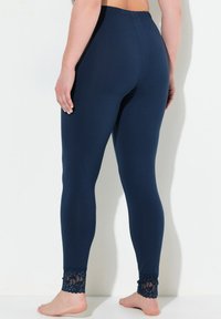 Námořnické legíny vyrobené z měkké tkaniny, s širokým elastickým pasem a krajkovým zdobením na okraji kotníku. Hladká textura po celé ploše.