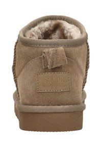 Bruine suède enkellaars met een zachte, fluffy voering, een ronde neus en een gestructureerde achterpaneel met een gestikt logo-patch.