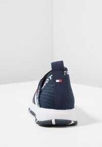 Zapatillas de lona azul marino sin cordones con tejido texturizado, suela media blanca y tirador en el talón con logotipo. Presentan un bloque de color sutil con acentos de logotipo.