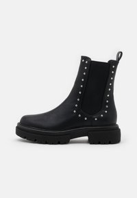 Black chelsea boots made of leather, featuring silver studs along the elastic side panels, textured rubber sole, and pull tab.
