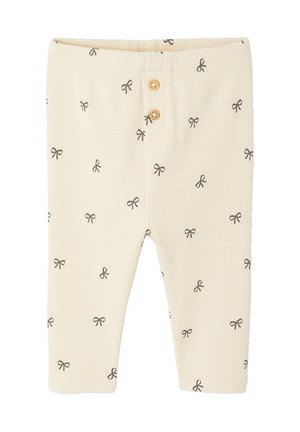 Cream-colored ribbed baby pants with small black bow patterns and two wooden buttons on the front waistband.