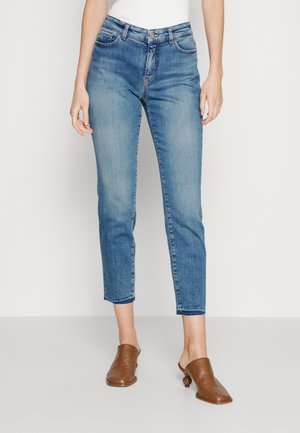 Jean sinisen mid-rise suoran leikkauksen, vaaleat pesut, viisi taskua, hienovarainen kuluminen ja lahkeet käännetty. Yhdistetty ruskeisiin mules-kenkiin.
