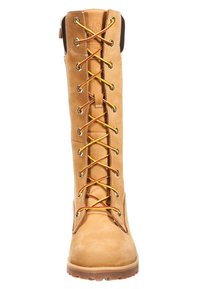 Bottes montantes à lacets en cuir couleur tan avec œillets métalliques et lacets multicolores. Semelle en caoutchouc avec des rainures pour une meilleure traction.