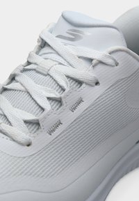 Άσπρο αθλητικό παπούτσι με επάνω μέρος από πλέγμα, υφασμάτινες πάνελ, επίπεδα κορδόνια και μαξιλαρωμένο γιακά. Λογότυπο ανάγλυφο στη γλώσσα και την πλευρά.