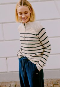 Pletený sveter s polovičným zipsom, s krémovými a námorníckymi pruhmi, kombinovaný s námorníckymi kordovými nohavicami s elastickým pásom a detailom vrecka.