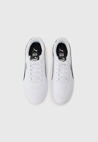 Baskets blanches avec des accents noirs, design à lacets, texture en cuir lisse et détails perforés sur la boîte à orteils et les côtés.
