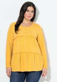 Langsleeve, gele top met een ronde hals, knoopsluiting en gelaagd volantsontwerp. Zacht, lichtgewicht materiaal met een licht gestructureerde afwerking.