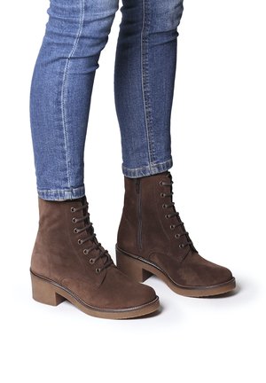 Stivaletti in suede marrone con tacco impilato, dotati di lacci e zip laterale. Design elegante con una superficie liscia e accenti minimi.