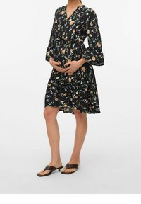 Abito materno nero a fiori con scollo a V, maniche a campana lunghe e vita con fiocco. Presenta motivi floreali colorati e una silhouette fluida.