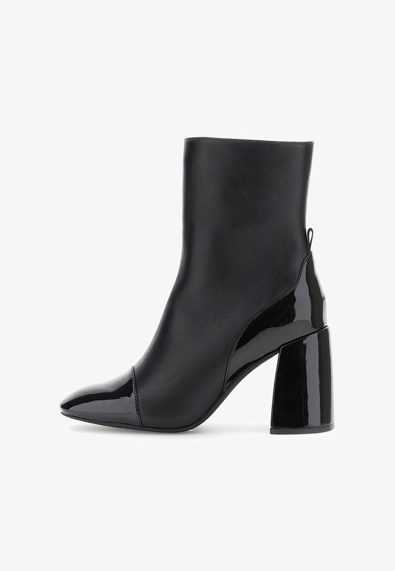 Černá kotníková bota vyrobená z hladké kůže s lesklou lakovanou špičkou a patou. Má zúžený tvar a design bloku podpatku.