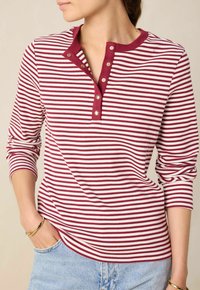 Rot-weißer gestreifter Langarm-Henley-Shirt mit gerippter Textur, drei goldenen Knöpfen und Rundhalsausschnitt. Lässige Passform.