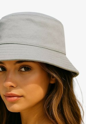 Lichtgrijze bucket hat van gestructureerde stof, met een brede rand en subtiele stiksel-details. Eenvoudig, minimalistisch ontwerp.