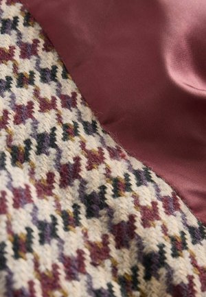 Wollstoff im Hahnentrittmuster in Creme-, Burgunder- und Schwarztönen, kombiniert mit glattem Burgunder-Satin. Strukturierte und kontrastreiche Oberflächen.