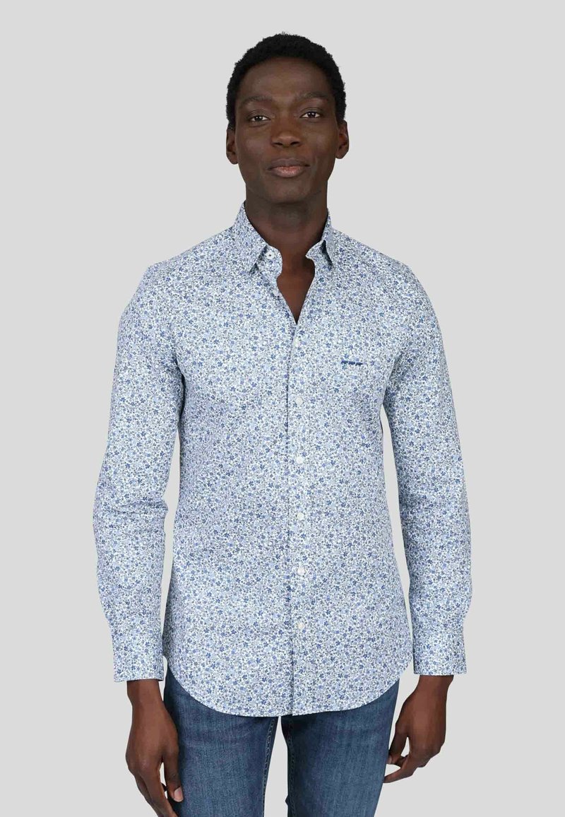 Chemise à boutons en bleu clair avec un motif floral. Manches longues et col pointu. Tissu en coton avec une texture douce.