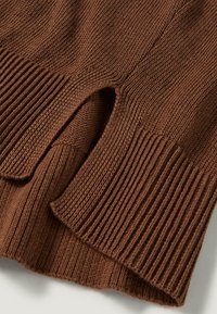 Brauner Strickpullover mit strukturiertem Finish, geripptem Saum und seitlichen Schlitzen für mehr Bewegungsfreiheit. Der Stoff wirkt weich und flexibel.