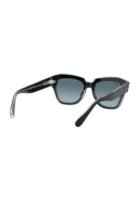 Gafas de sol estilo cat-eye en color negro con lentes degradados, bordes claros y brazos negros robustos. Presentan acentos plateados en el marco para un diseño elegante.