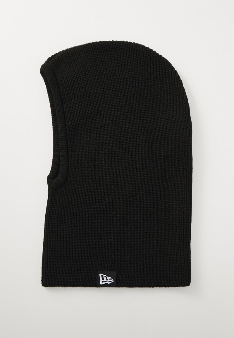 Black knit beanie with a textured pattern, elongated shape, and a small white logo patch at the bottom edge.