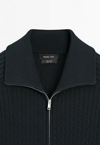 Maglione nero in cotone a maglia treccia con cerniera argentata e ampio colletto a costine, etichettato Massimo Dutti, prodotto in Cina.