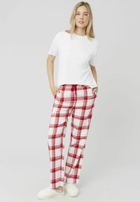 T-shirt blanc, pantalon à carreaux rouge et blanc avec une taille élastique et un cordon de serrage ; modèle portant des chaussons blancs texturés.