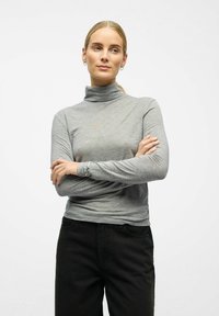 Dugi rukav sivi rolak u glatkom, rastezljivom materijalu s prilagođenim dizajnom. Ima visoki ovratnik i jednostavne, čiste linije.