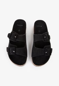 Sorte ruskind slide sandaler med to justerbare spænder, åben tå-design og en naturligt struktureret sål. Størrelse 37 vises indeni.