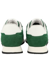 Sneaker verde e bianco realizzate con materiali scamosciati e sintetici, colletto imbottito e suola in gomma nera. Design classico delle scarpe da corsa.