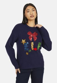 Maglione blu navy con design di paillettes con la parola "ELF", un fiocco rosso e stelle colorate. Realizzato in tessuto morbido con vestibilità comoda.