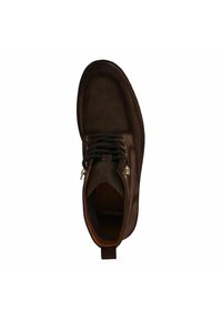 Stivale alla caviglia in suede marrone con punta tondeggiante, chiusura con lacci e occhielli in metallo. Presenta una suola cucita e una corta linguetta sul retro.