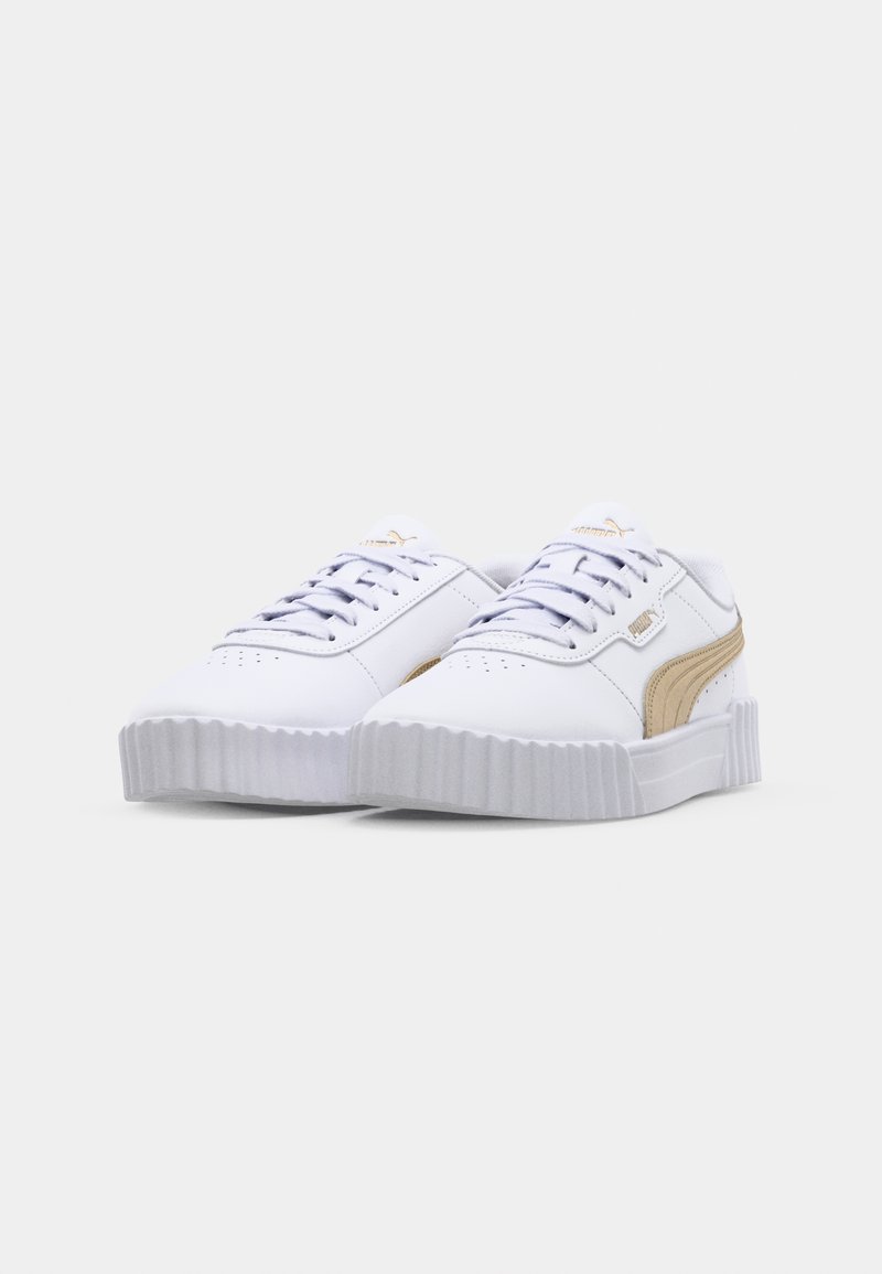 Baskets blanches avec des semelles en caoutchouc texturé, présentant une bande latérale beige et des lacets blancs. Tige en synthétique lisse, design à bout rond.