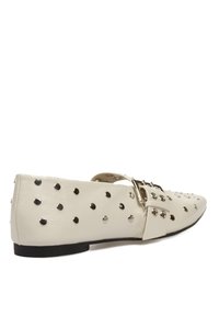 Bailarinas de cuero blanco con tachuelas plateadas, punta afilada y hebilla lateral. Presentan una textura suave y un diseño minimalista.