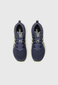 Navy athletic shoes with mesh upper, textured surface, reflective accents, and lime green sole. Features laces and supportive structure.