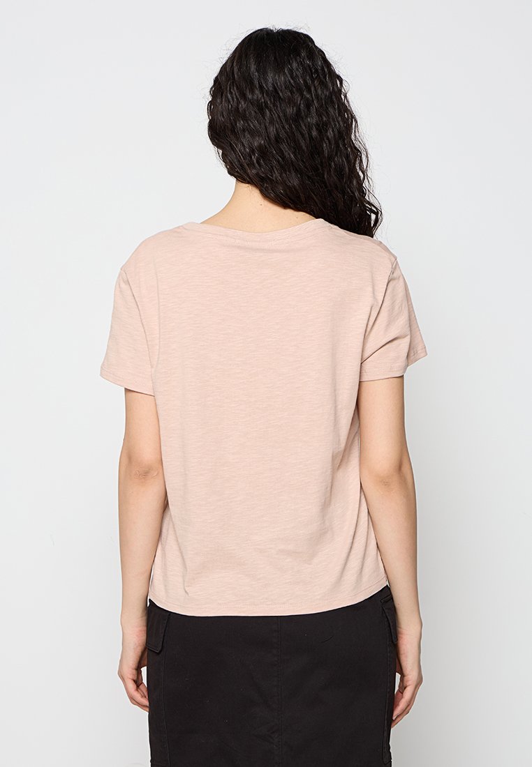Maglietta a maniche corte, rosa chiaro, con scollatura rotonda, texture morbida e taglio rilassato. Il retro presenta un design semplice senza decorazioni.