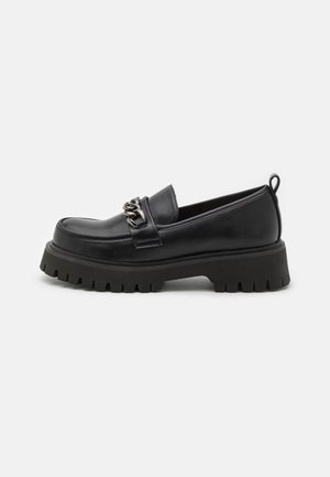 Zwarte leren loafer met grove grof profielzool en zilveren kettingdetail over de wreef, voorzien van een treklipje aan de hiel.