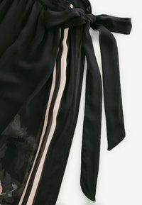 Crni materijal s vezanjem u struku, s dvije okomite bež pruge. Materijal je proziran s nježnim cvjetnim uzorcima.