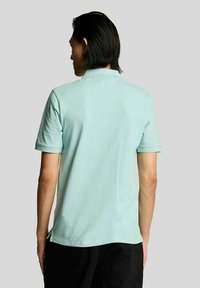 Lichtblauw, kortärmelig poloshirt met een klassieke kraag. Gemaakt van katoen, heeft een gladde textuur en zijsplitten aan de onderkant voor gemak.