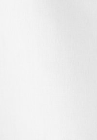 Biały materiał o fakturze z subtelnym wzorem tkanym i lekkimi gradientami cieni na powierzchni.