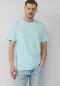 Jasnoniebieska bawełniana koszulka z okrągłym dekoltem i krótkimi rękawami, z małym logo na piersi i luźnym krojem.