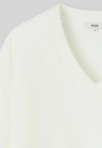 Pull col V blanc en tissu doux, doté de poignets et d'un ourlet côtelés, idéal pour le superposition ou un look décontracté, disponible en taille petite.