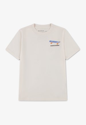 T-shirt crème à manches courtes pour enfant avec un petit skateboard bleu et orange et le texte "ABERCROMBIE" sur la partie supérieure gauche de la poitrine.